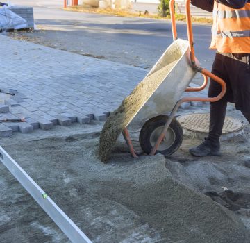 Pouring sand from wheelbarrow onto footpath in preparation for laying of decorative stones